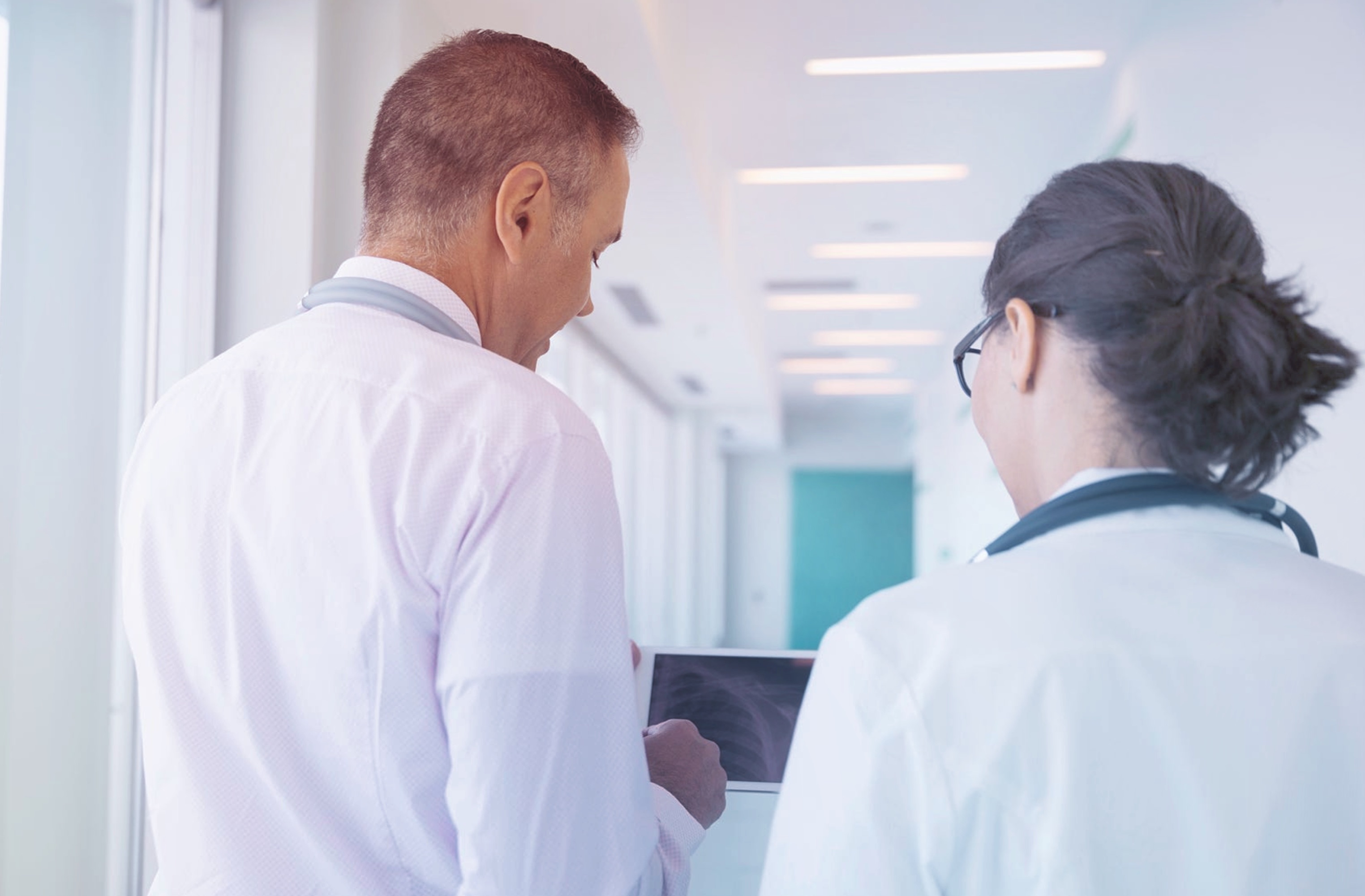 Two doctors looking at X-rays on a handheld tablet device
